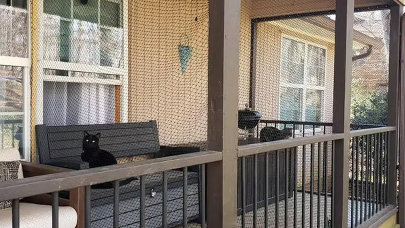 Black cat net enclosure across an outdoor terrace boundary